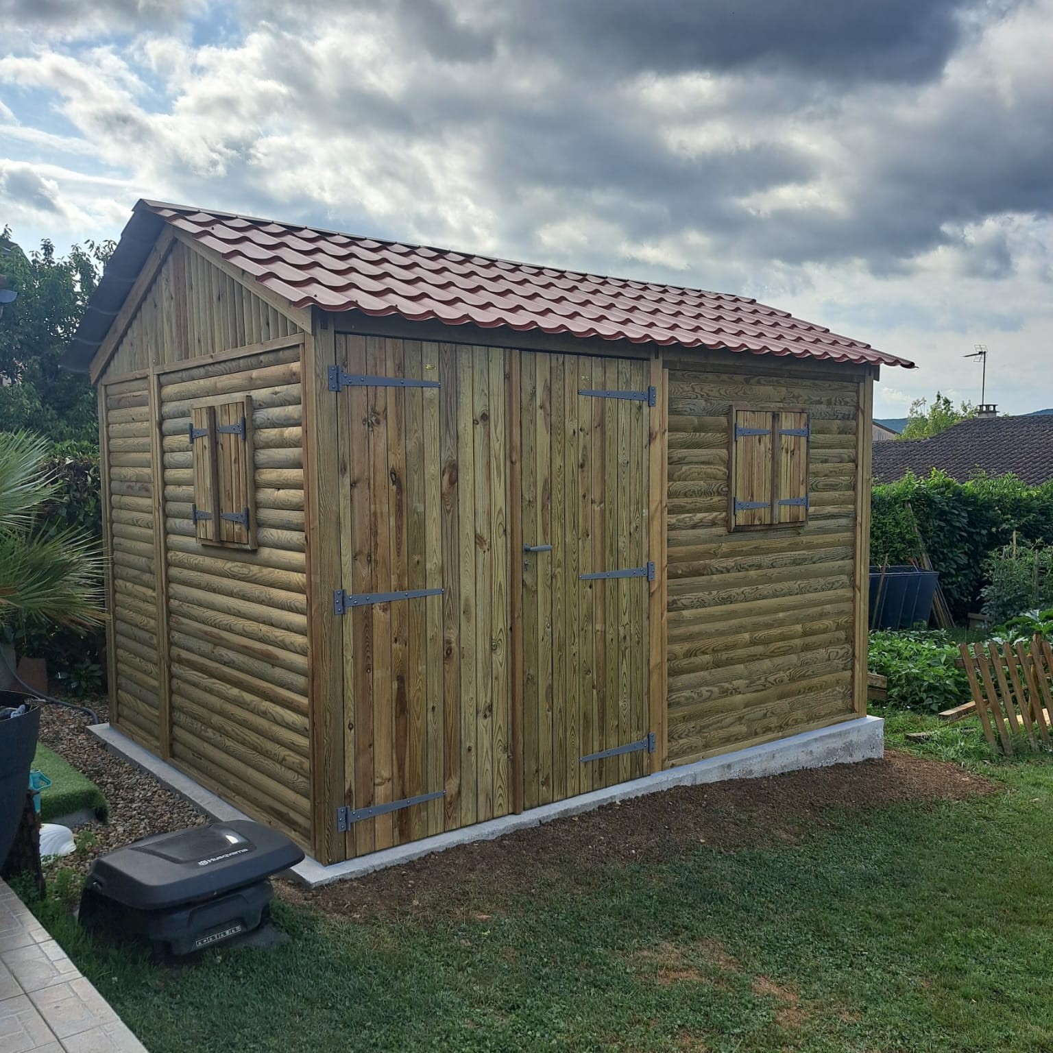 Abri bois extérieur installé dans un jardin avec structure en bois sur mesure servant de local jardin pratique et esthétique