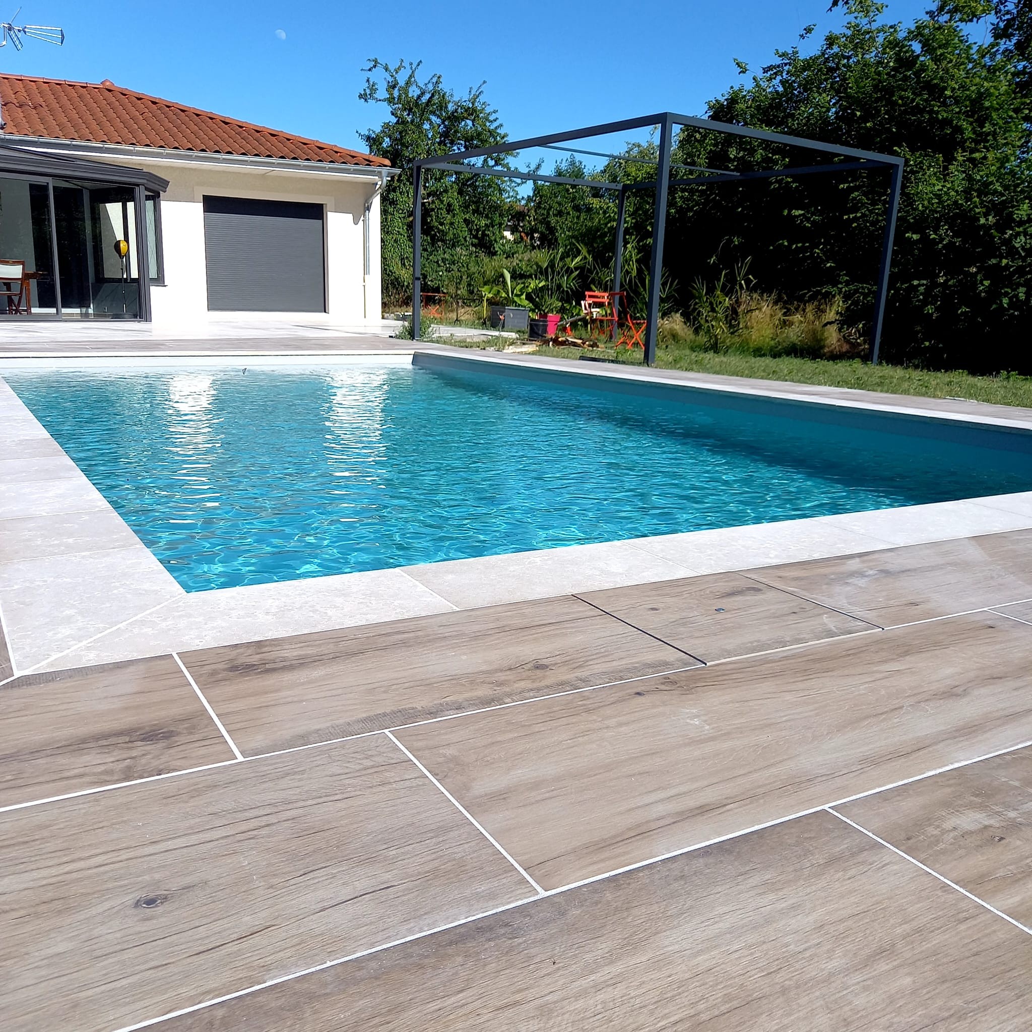 Aménagement extérieur en maçonnerie paysagère autour de piscine avec terrasse et espace détente.